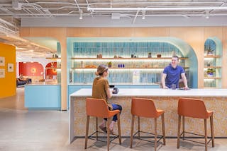A tea point allows staffers to connect over tea and coffee. Lucifer Cylinder lights provide bright ambient lighting. The co-working area in the background features Pilot chandeliers and Radient Disc sconces from Rich Brilliant Willing.