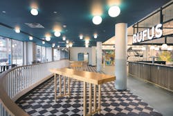 The black-and-white patterned floor, wood-textured bar wall, and striking blue ceiling provide examples of how the design team at TAT incorporated colors and textures on every plane in this eclectic interior space.