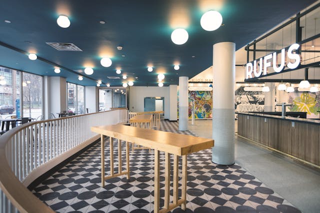 The black-and-white patterned floor, wood-textured bar wall, and striking blue ceiling provide examples of how the design team at TAT incorporated colors and textures on every plane in this eclectic interior space.
