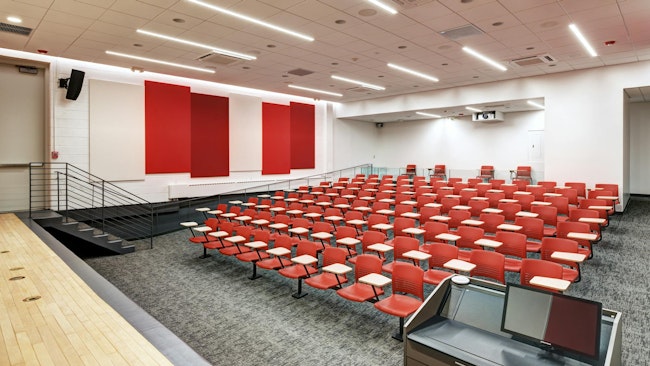 To light the lecture hall, overhead recessed downlights, cove lighting along the aisles, and decorative linear LEDs were incorporated into acoustic panels on the side walls.